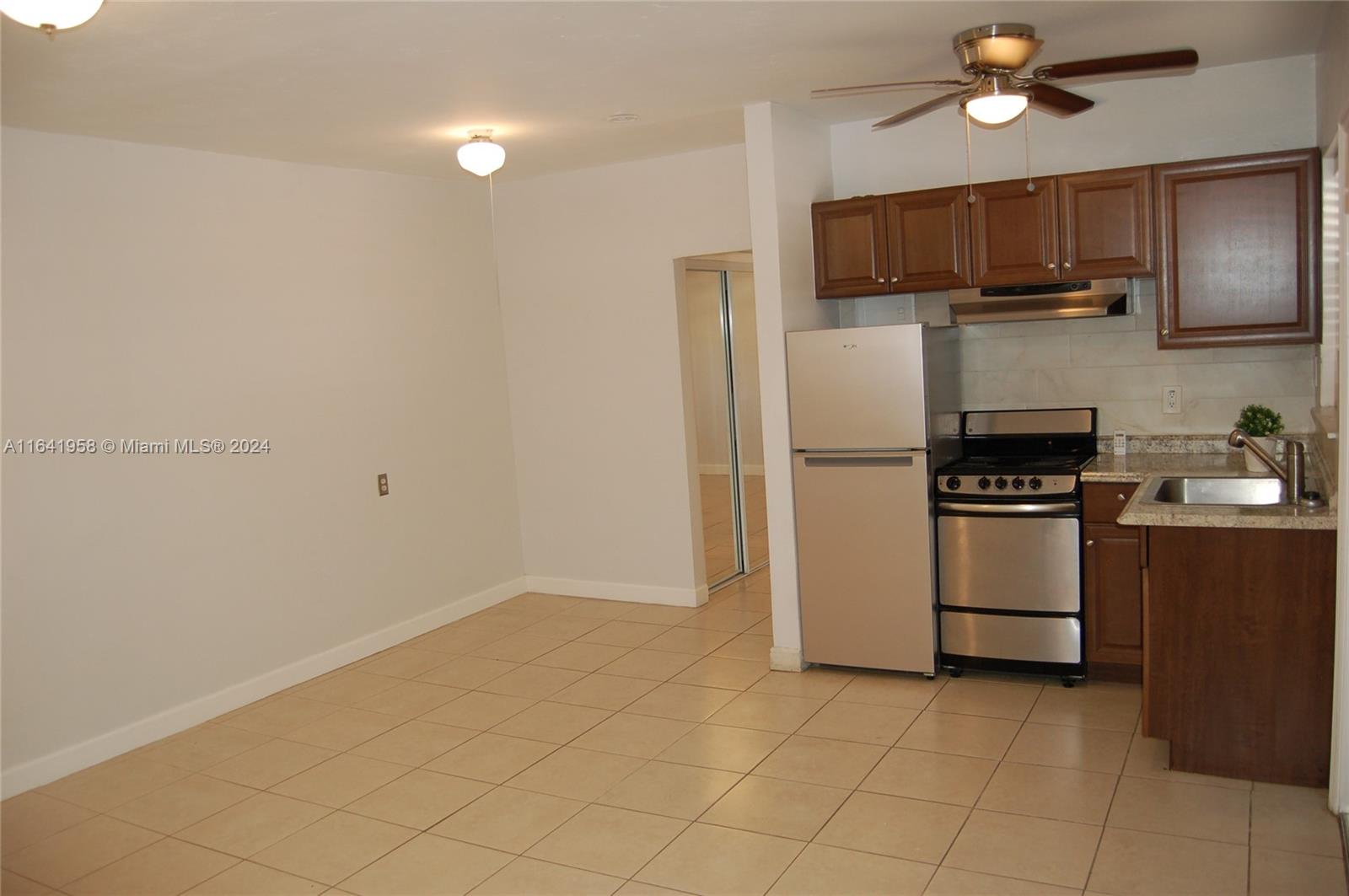 2481 Southwest 11th Street, Unit 2481 Miami, FL 33135 - Photo 4 of 9 a kitchen with a refrigerator a stove top oven a kitchen island and cabinetry