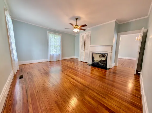 an empty room with wooden floor fireplace and windows