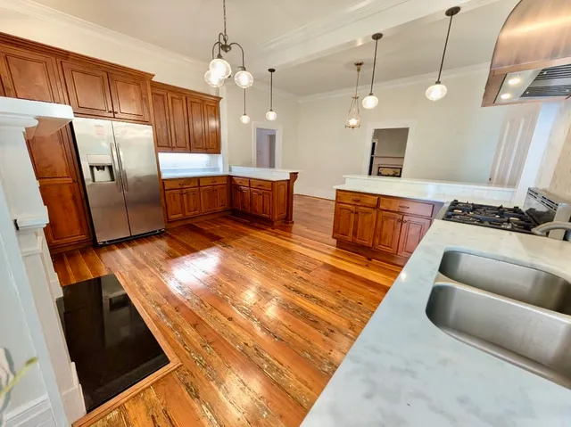 a kitchen with stainless steel appliances kitchen island granite countertop a sink dishwasher and a couch with wooden floor