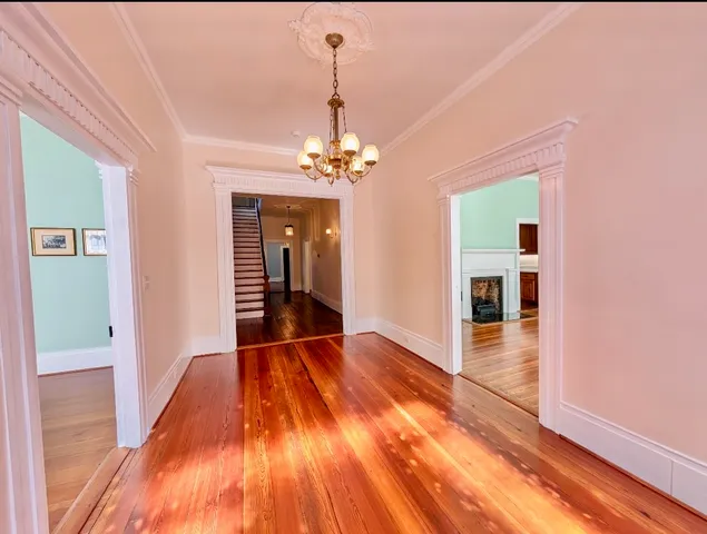 a view of a hallway with wooden floor and a chandelier