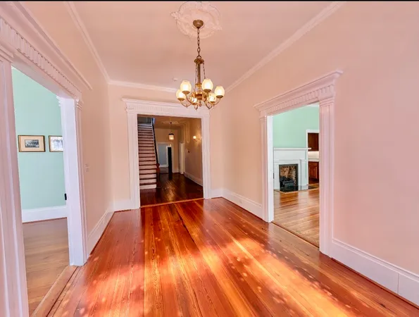 a view of a hallway with wooden floor and a chandelier