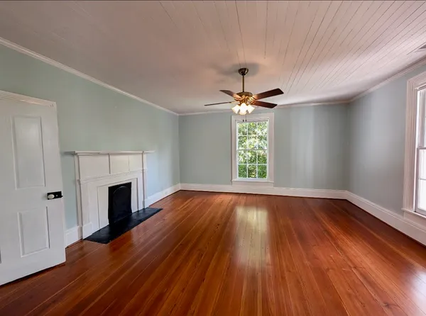 an empty room with wooden floor fireplace and windows