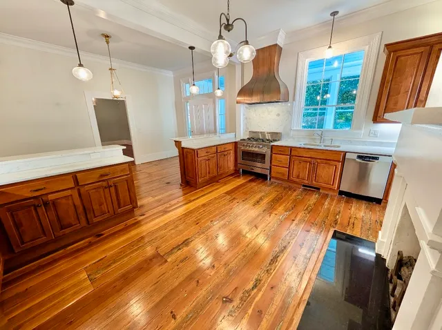 a large kitchen with a sink stove and wooden floor