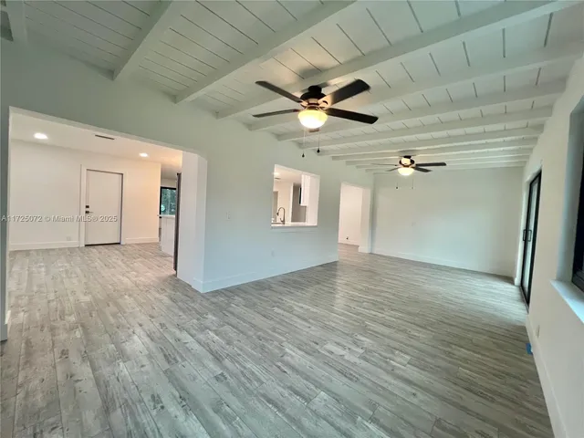 a view of empty room with wooden floor and ceiling fan