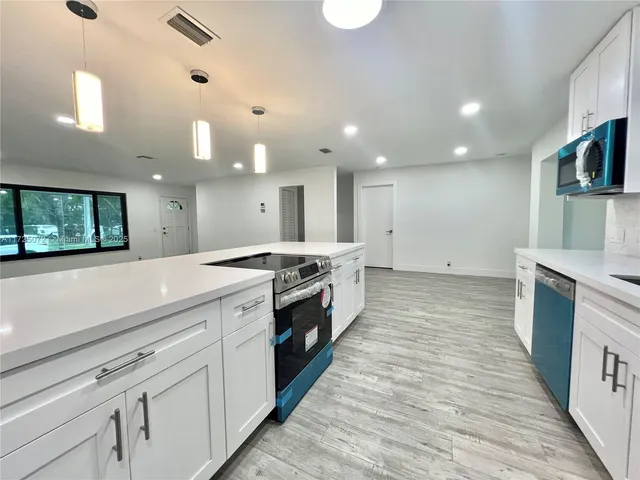 a large kitchen with stainless steel appliances kitchen island granite countertop a large counter top and a stove top oven