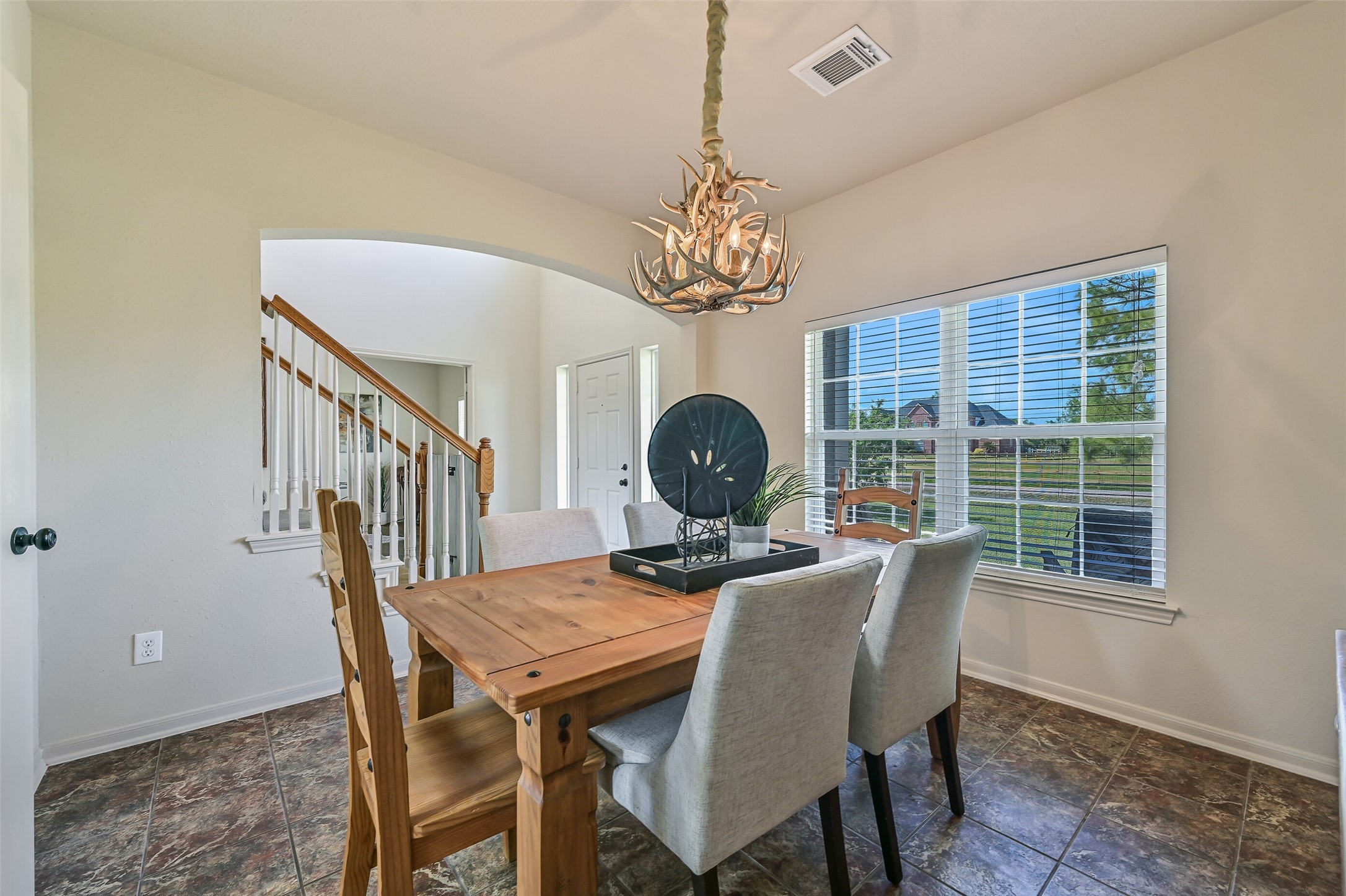1404 Hollier Road Friendswood, TX 77546 - Photo 11 of 46 Continue into the dining room where a vaulted ceiling and statement chandelier create an inviting space for gatherings. Large windows overlook the front acreage, bringing in natural light and enhancing the open feel of the home.