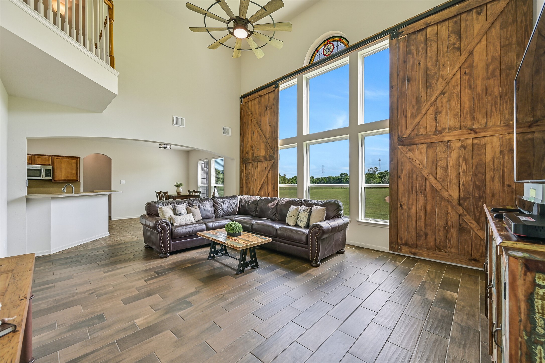 1404 Hollier Road Friendswood, TX 77546 - Photo 14 of 46 A wider view of the family room highlights the scale and openness, with wood-look flooring and a seamless connection to the main living areas. The barn-style window coverings create a striking focal point while maintaining privacy when desired.
