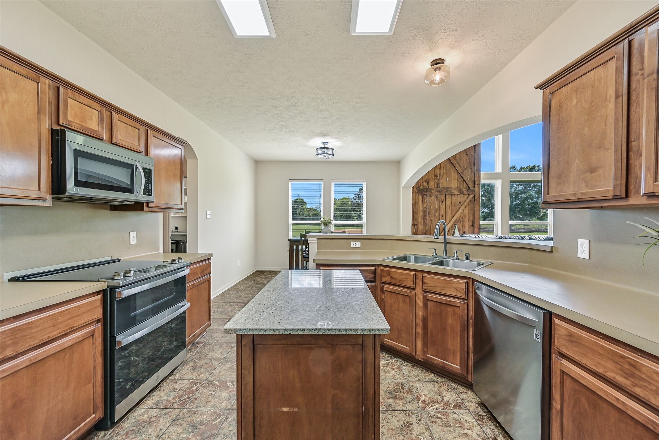 1404 Hollier Road Friendswood, TX 77546 - Photo 19 of 46 Another view of the kitchen highlights the open connection to the breakfast area and living room beyond. A large pass-through keeps the space feeling connected, while natural light and views of the acreage carry throughout.