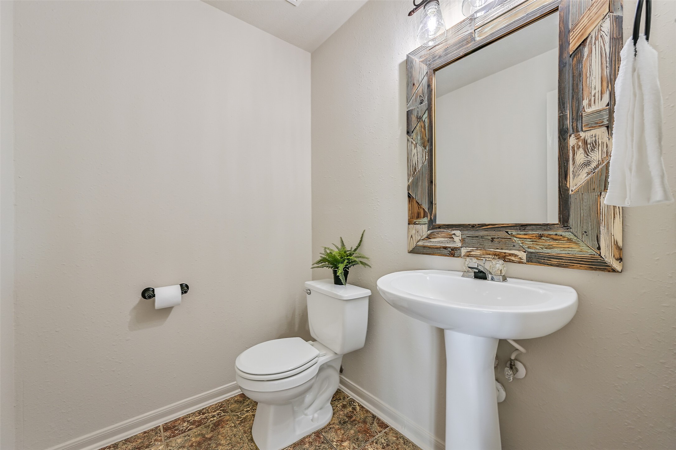 1404 Hollier Road Friendswood, TX 77546 - Photo 20 of 46 A convenient half bath is located on the main level, featuring a pedestal sink and a custom rustic mirror that adds character. Neutral finishes keep the space clean and cohesive with the rest of the home.