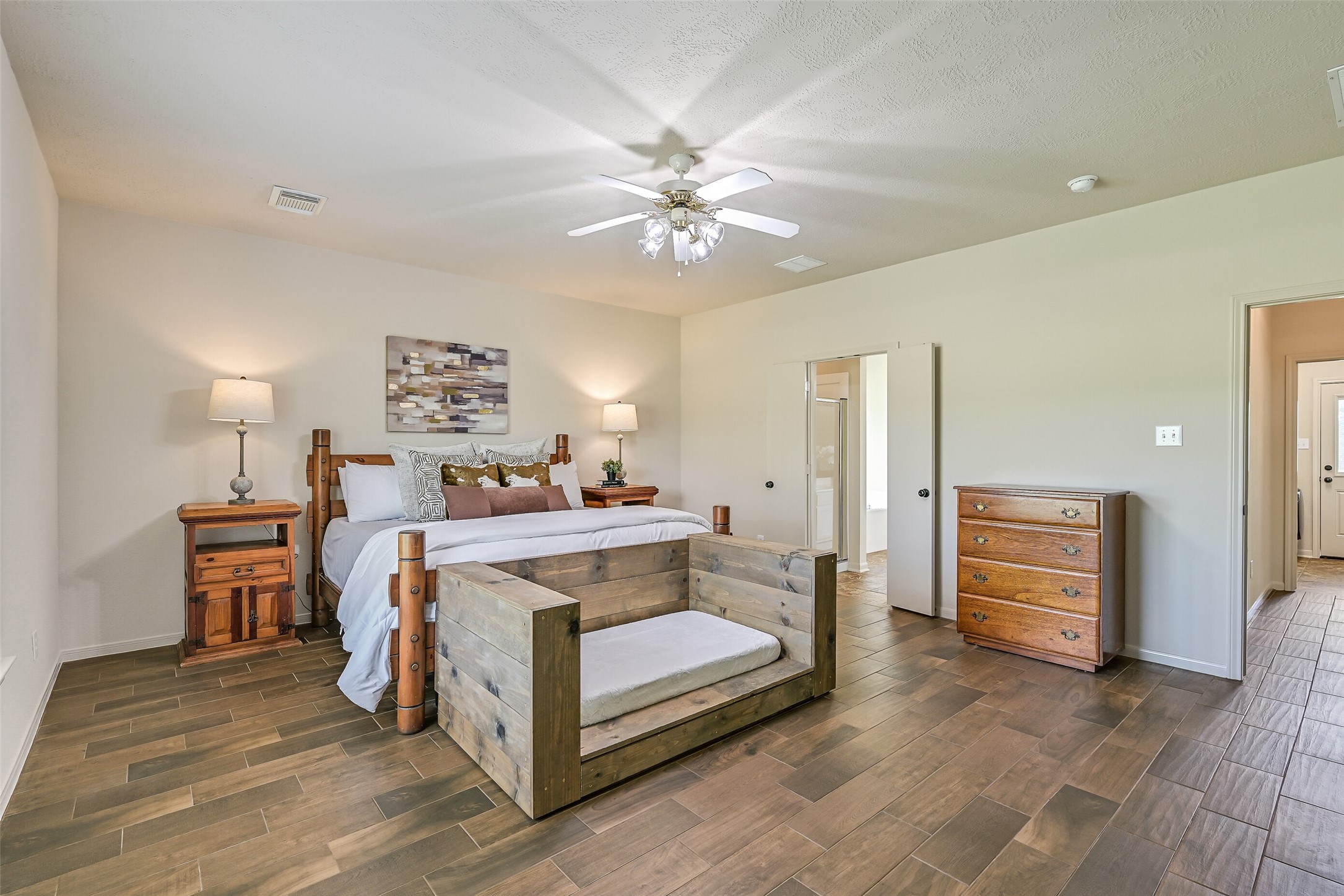 1404 Hollier Road Friendswood, TX 77546 - Photo 22 of 46 The spacious primary suite is tucked away on the first floor, offering privacy and room to unwind. Wood-look tile flooring, neutral tones, and natural light create a comfortable retreat with plenty of layout flexibility.