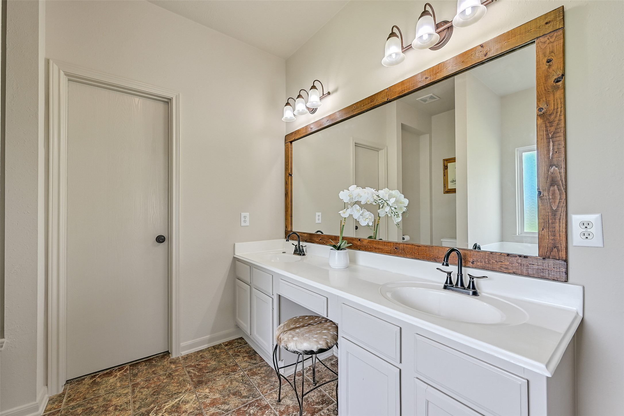 1404 Hollier Road Friendswood, TX 77546 - Photo 23 of 46 The primary bathroom features an extended vanity with dual sinks, ample counter space, and a large framed mirror with updated lighting. The layout is both functional and spacious, also offering a seated vanity space.