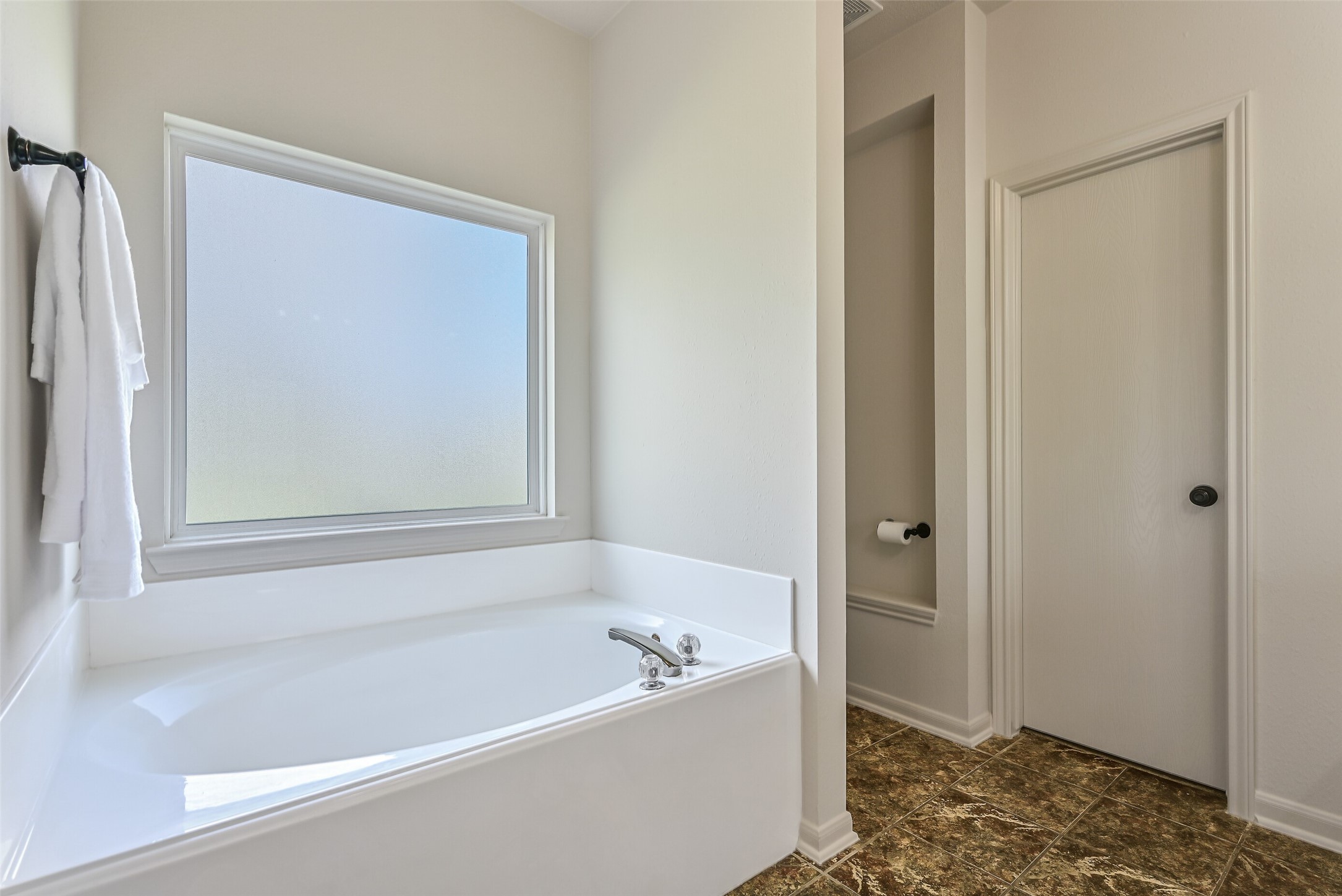 1404 Hollier Road Friendswood, TX 77546 - Photo 24 of 46 Enjoy a relaxing soaking tub positioned beneath a frosted window for natural light and privacy. The bathroom layout offers separation between vanity and bathing areas for added convenience.