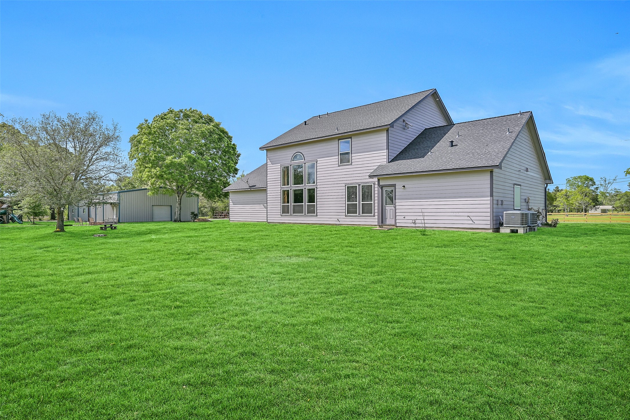 1404 Hollier Road Friendswood, TX 77546 - Photo 31 of 46 A rear view of the home highlights the wall of windows and the openness of the surrounding land. The setting feels private and unrestricted, with space that extends well beyond the immediate backyard.
