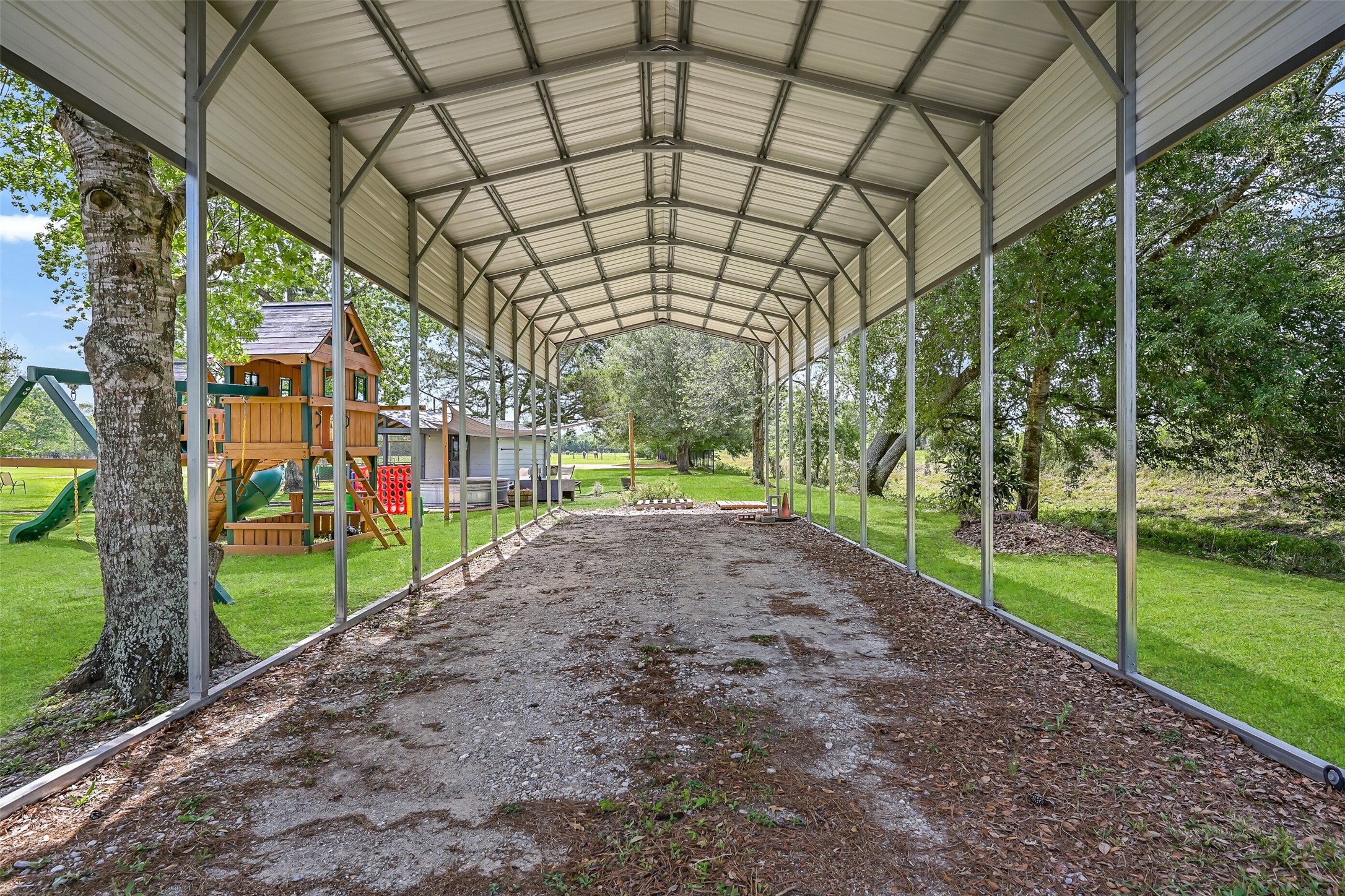 1404 Hollier Road Friendswood, TX 77546 - Photo 37 of 46 Covered RV parking measures approximately 45 feet deep, 16 feet wide, and 14 feet high, offering ample space for larger vehicles, trailers, or equipment. Positioned near the metal building, this setup adds convenience and flexibility for storage or travel needs.