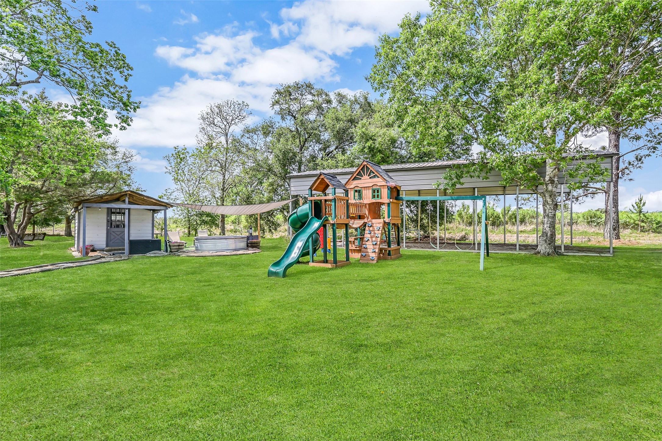 1404 Hollier Road Friendswood, TX 77546 - Photo 38 of 46 A wide view captures the layout of key amenities, including the 40’x80’ metal building, covered RV parking, playground, and cowboy pool. The spacing between each feature allows for multiple uses while maintaining an open, usable yard.