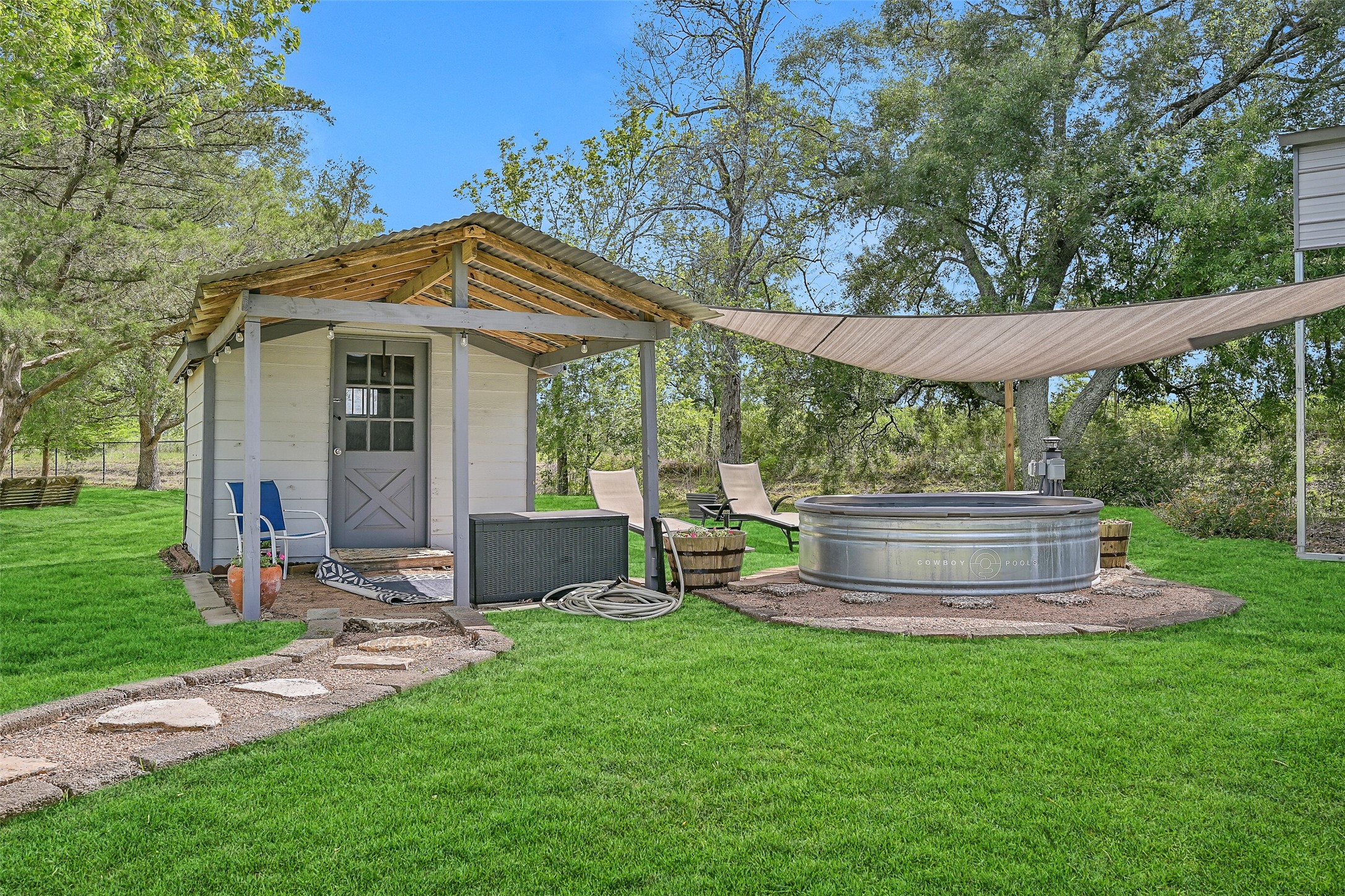 1404 Hollier Road Friendswood, TX 77546 - Photo 39 of 46 A dedicated outdoor setup includes a cowboy pool with a circulating filtration system, shaded seating, and a nearby structure for storage or changing space. This area adds a relaxed, functional retreat within the property.