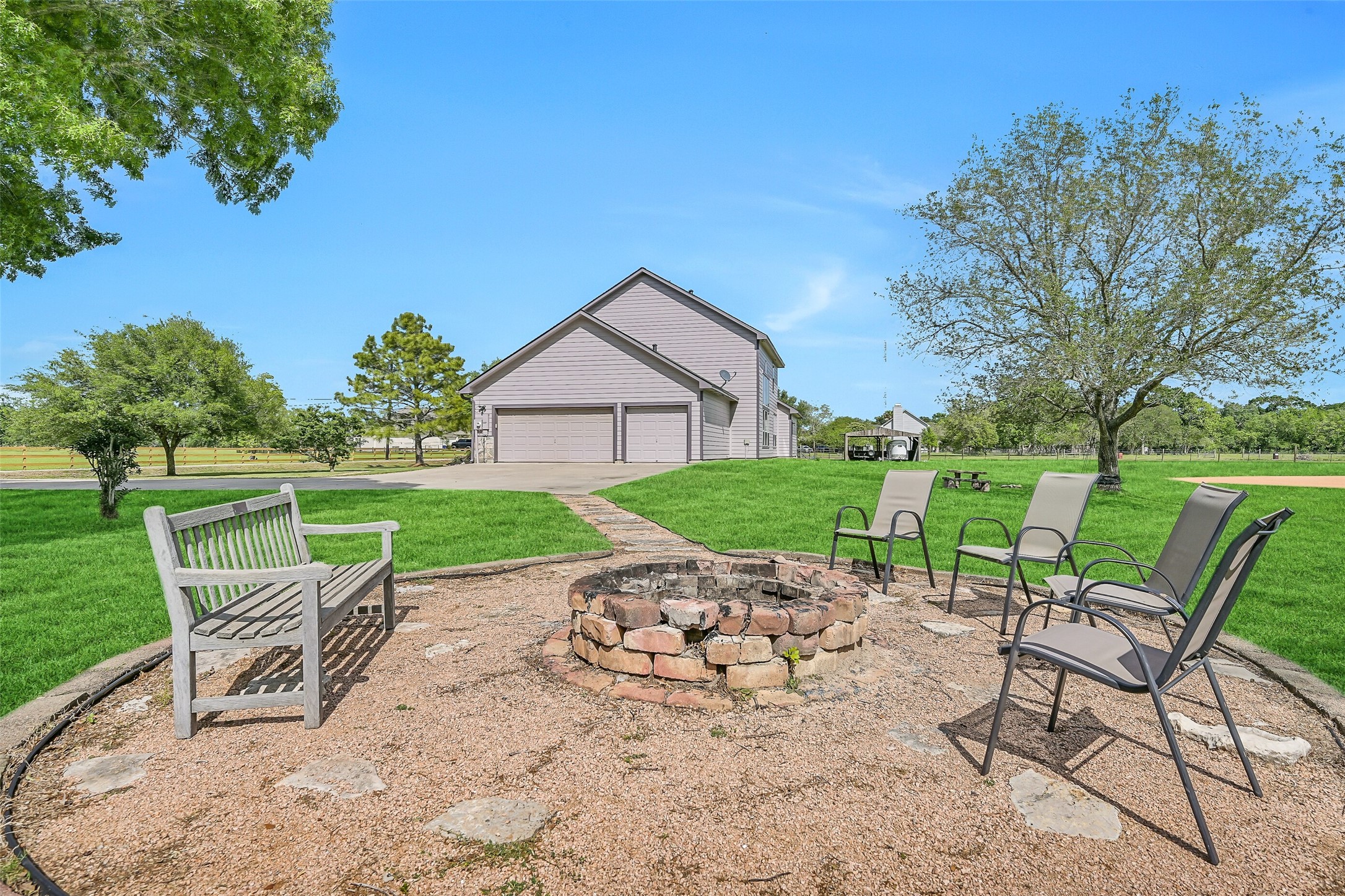 1404 Hollier Road Friendswood, TX 77546 - Photo 40 of 46 The fire pit area creates a natural gathering spot, surrounded by open lawn and views of the home and baseball diamond. A simple layout with seating space makes it easy to enjoy evenings outdoors.
