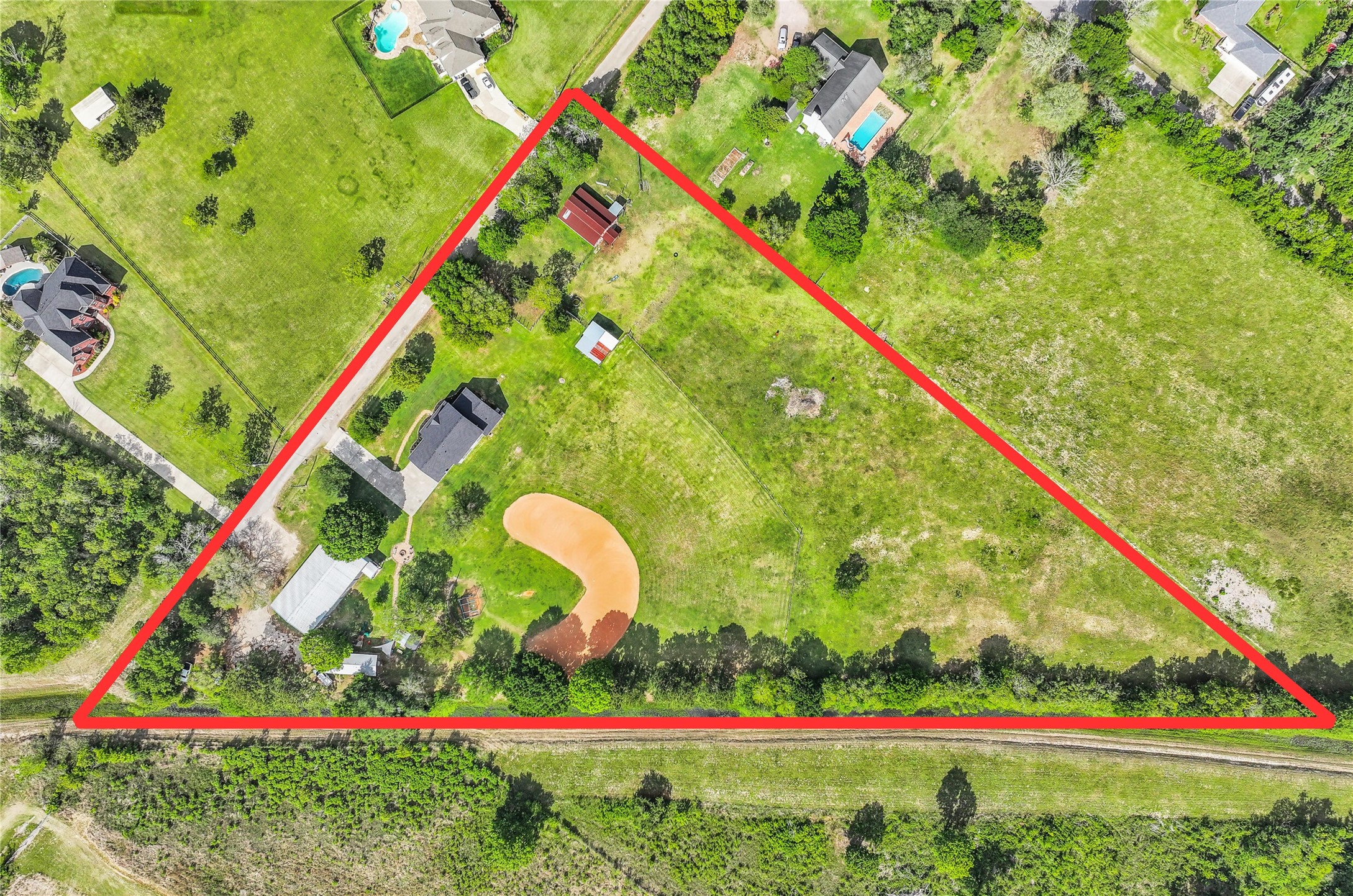 1404 Hollier Road Friendswood, TX 77546 - Photo 43 of 46 An overhead view outlines the approximate boundaries of this 6+ acre property, showcasing the full layout including the home, barn, metal building, baseball field, & open pasture. The triangular shape offers both privacy & functional separation of spaces.
