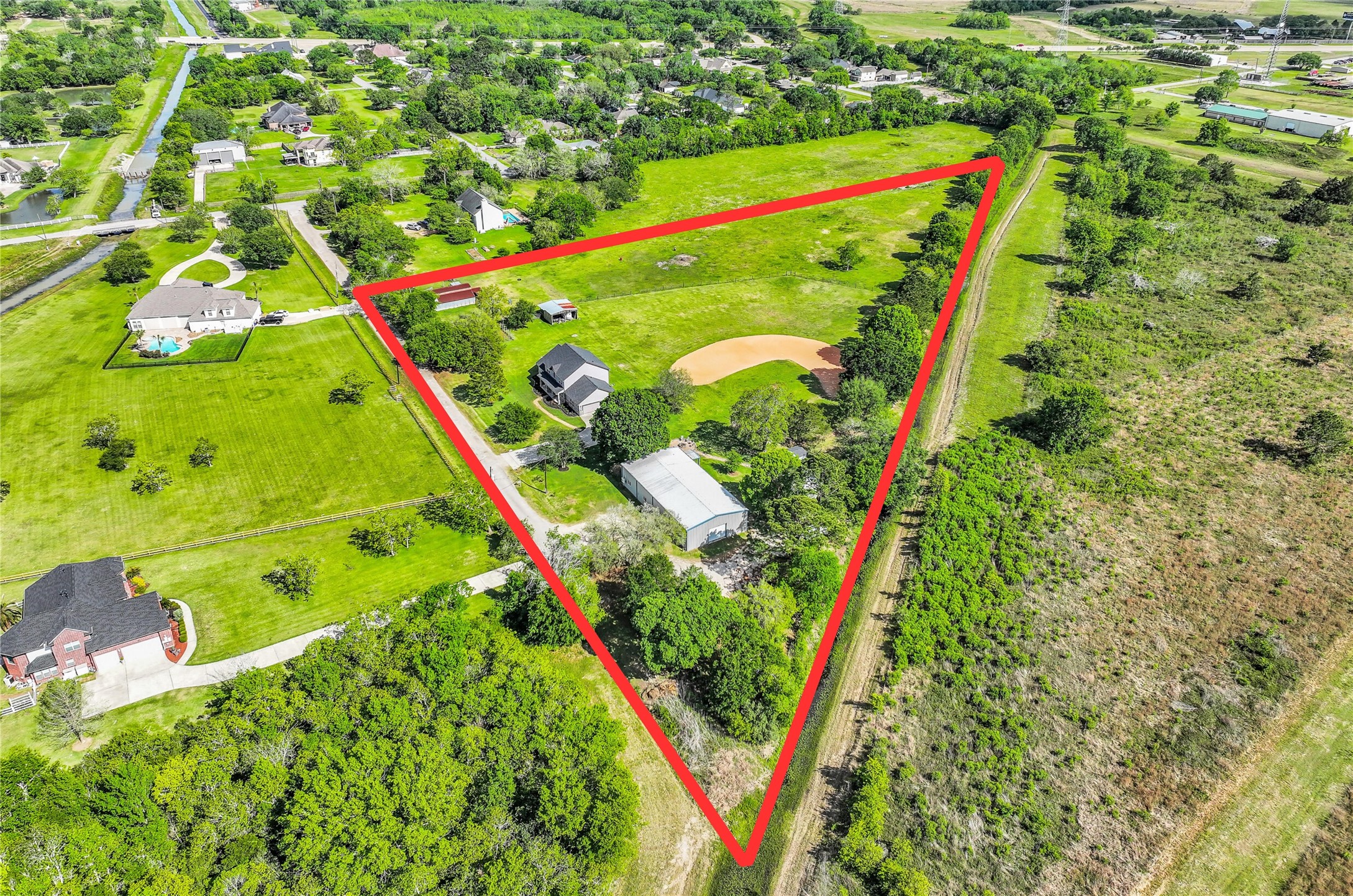 1404 Hollier Road Friendswood, TX 77546 - Photo 46 of 46 This perspective shows the depth of the property from front to back, with cross-fenced pasture, mature tree lines, and multiple structures already in place. The layout supports livestock, recreation, or future expansion.