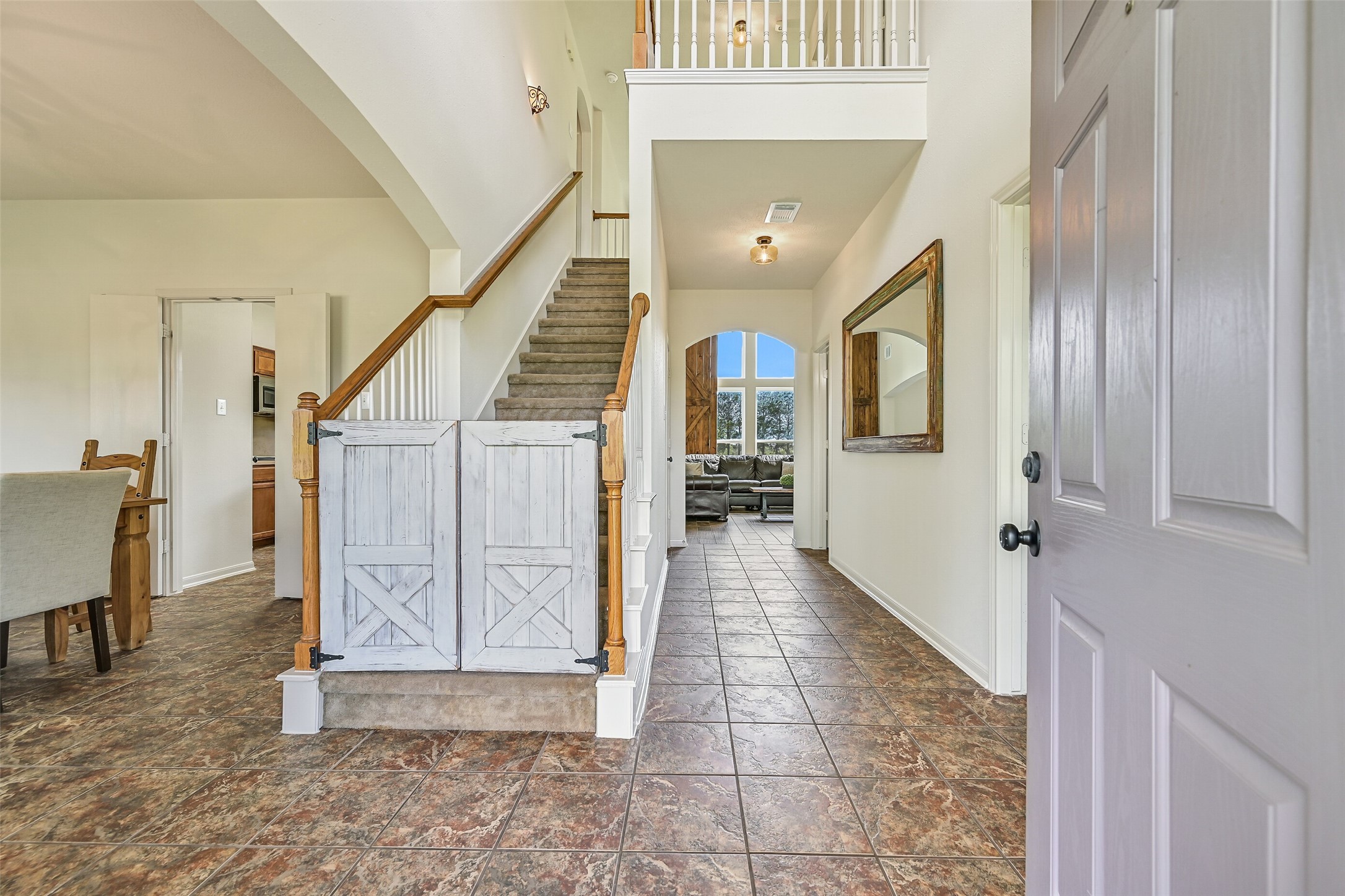 1404 Hollier Road Friendswood, TX 77546 - Photo 8 of 46 Step inside to a welcoming foyer with tile flooring and a clear sightline to the back of the home. The staircase is accented with a custom barn-style gate, while the open layout and double-paned windows bring in natural light throughout.