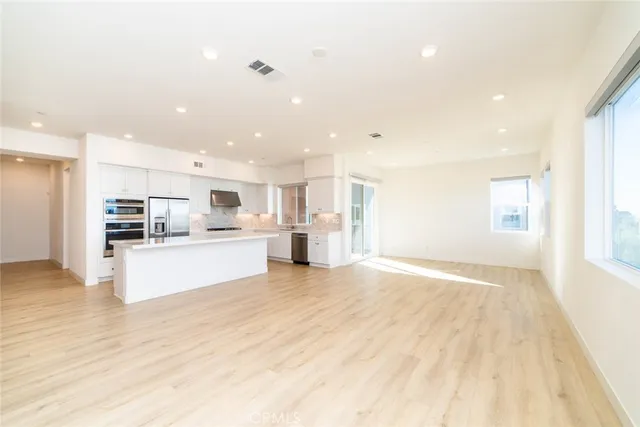 a view of kitchen with kitchen island wooden floor center island and stainless steel appliances