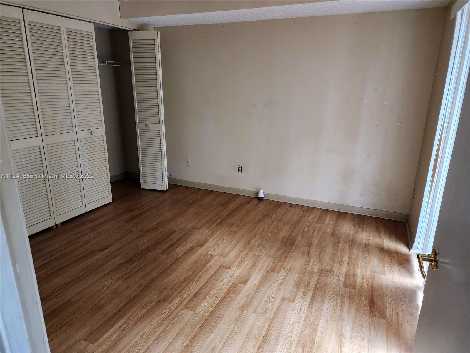 8139 Boca Rio Drive, Unit 8139 Boca Raton, FL 33433 - Photo 7 of 23 a view of an empty room with wooden floor and a window