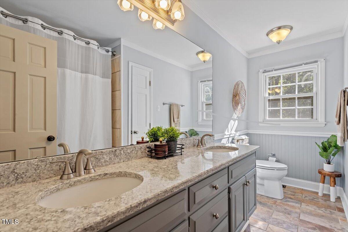 4912 Elizabeth Drive Raleigh, NC 27604 - Photo 21 of 35 a bathroom with double vanity sinks a toilet and a mirror