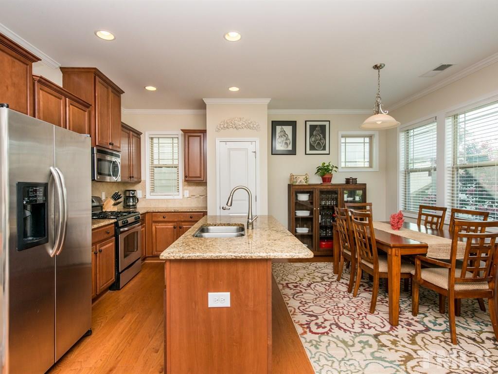 1310 Rodessa Run Raleigh, NC 27607 - Photo 2 of 25 a open kitchen with stainless steel appliances granite countertop a stove top oven a sink dishwasher a dining table and chairs with wooden floor