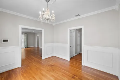 a view of a big room with wooden floor chandelier and windows