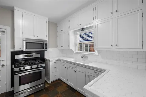 a kitchen with white cabinets and appliances