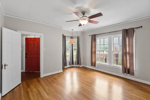 a view of an empty room with wooden floor and a window