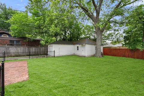 a view of a yard in front of a house with large tree