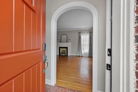 an empty room with wooden floor fireplace and windows