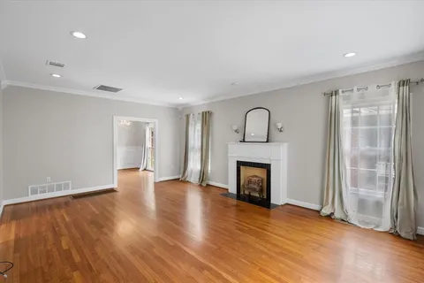an empty room with wooden floor fireplace and windows