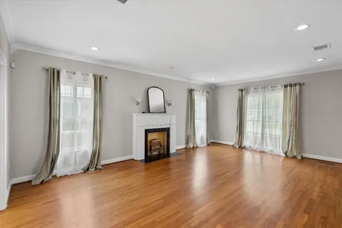 a view of an empty room with wooden floor fireplace and a window