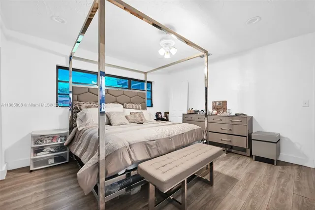 a bedroom with a bed a dresser and wooden floor