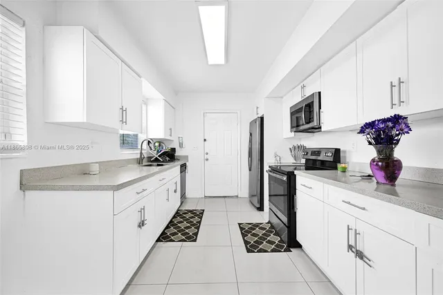 a kitchen with granite countertop a sink stainless steel appliances and white cabinets