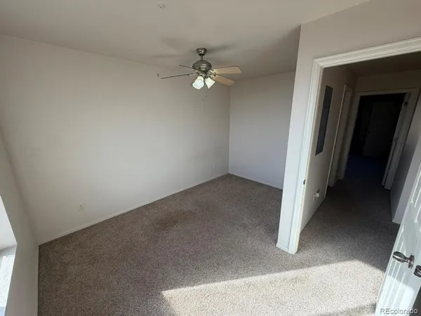 an empty room with a ceiling fan and a window
