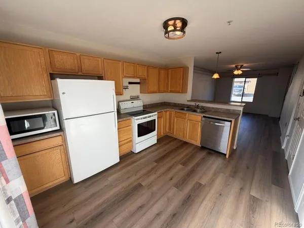 a kitchen with wooden floors and white appliances