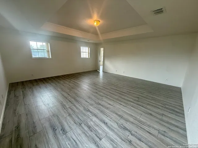 an empty room with wooden floor and windows