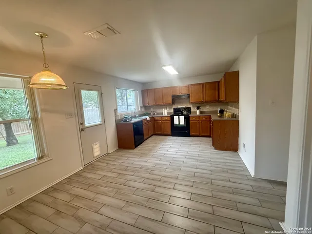 a kitchen with stainless steel appliances granite countertop a refrigerator a sink dishwasher a stove and a refrigerator with wooden floor