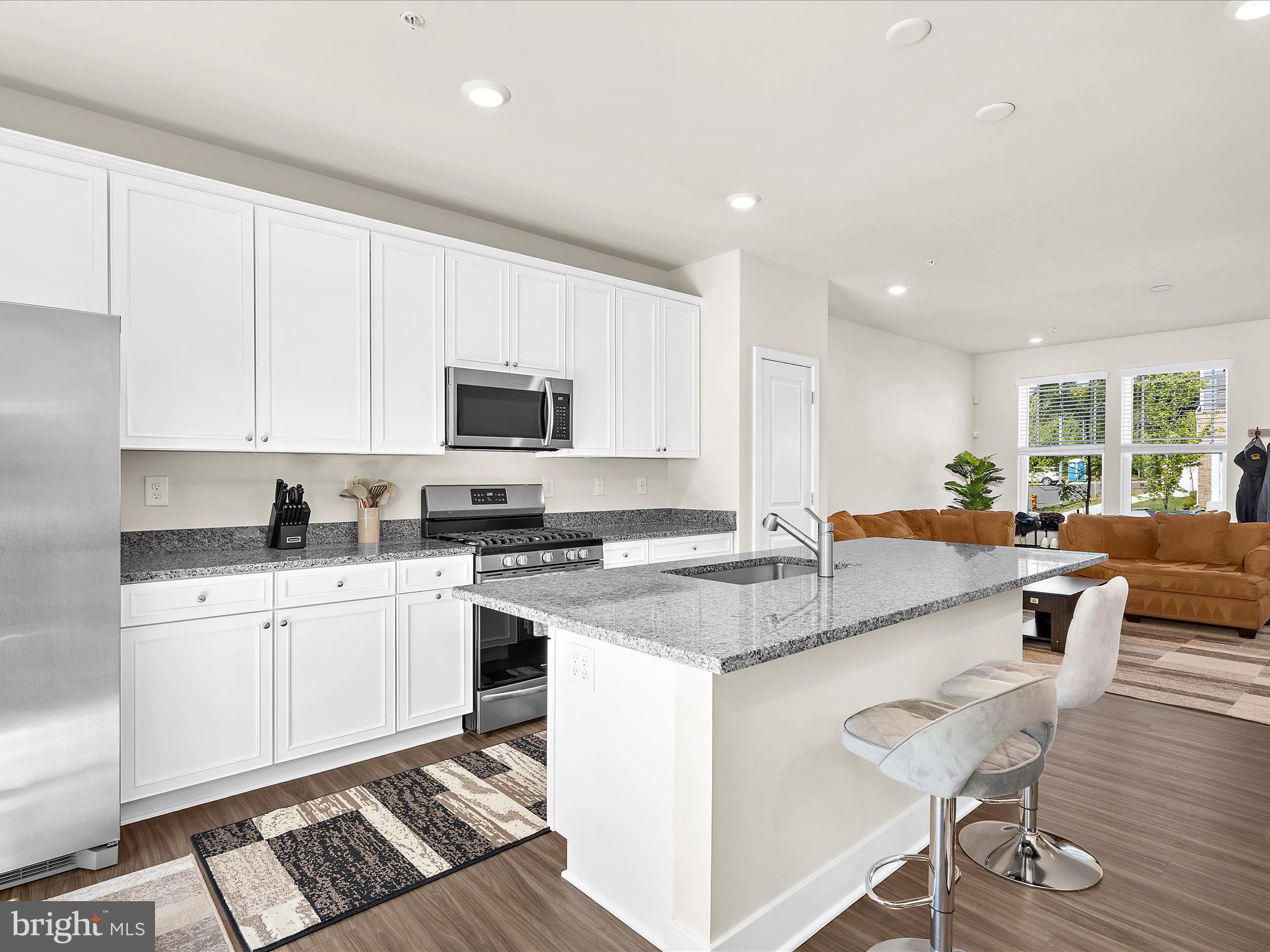 2324 Woodlands Road Baltimore, MD 21244 - Photo 14 of 44 a kitchen with stainless steel appliances granite countertop a stove top oven a sink a dining table and chairs with wooden floor