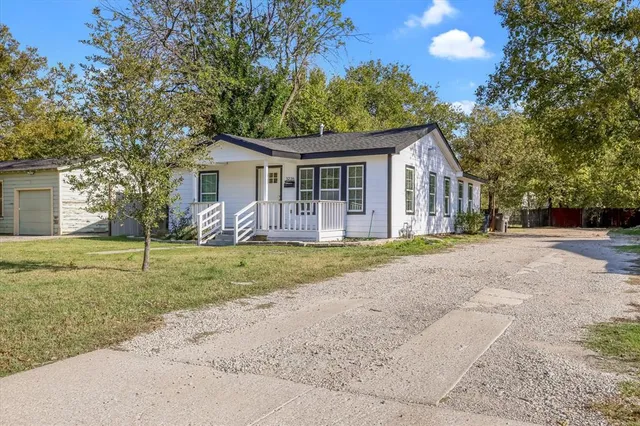 a view of a house with a yard and large trees