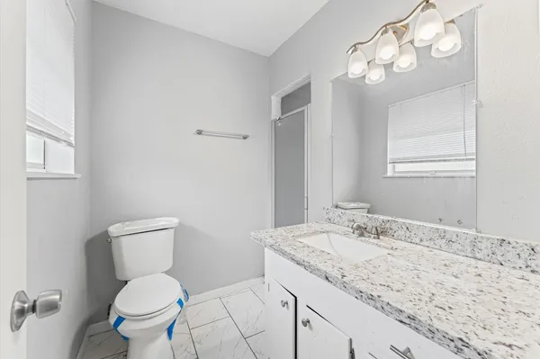 a bathroom with a granite countertop toilet sink and mirror