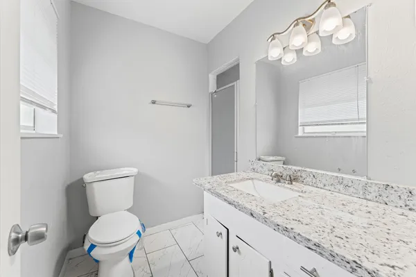 a bathroom with a granite countertop toilet sink and mirror