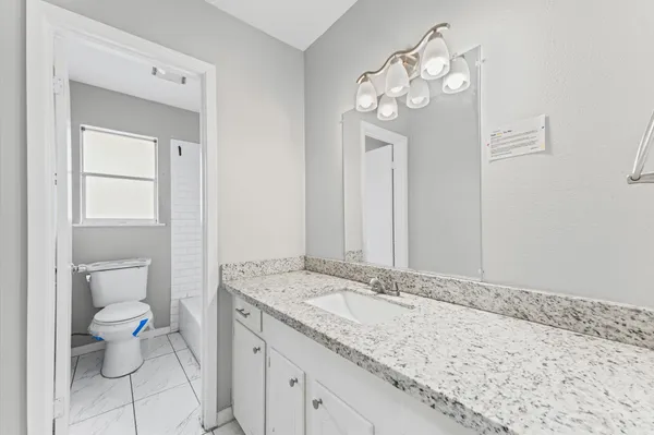 a bathroom with a granite countertop sink a toilet and a mirror