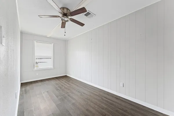 a view of an empty room with window and wooden floor