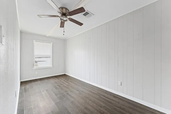 a view of an empty room with window and wooden floor