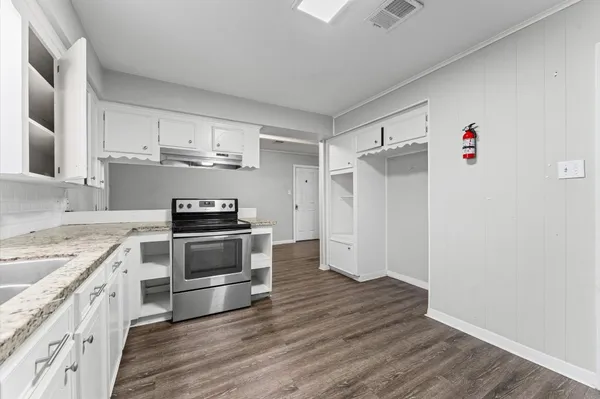 a kitchen with cabinets wooden floor and stainless steel appliances