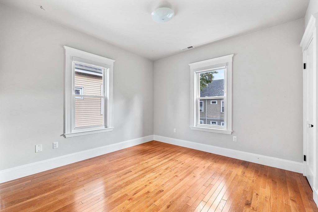 582 High Street, Unit 2 Medford, MA 02155 - Photo 18 of 27 a view of an empty room with wooden floor and a window